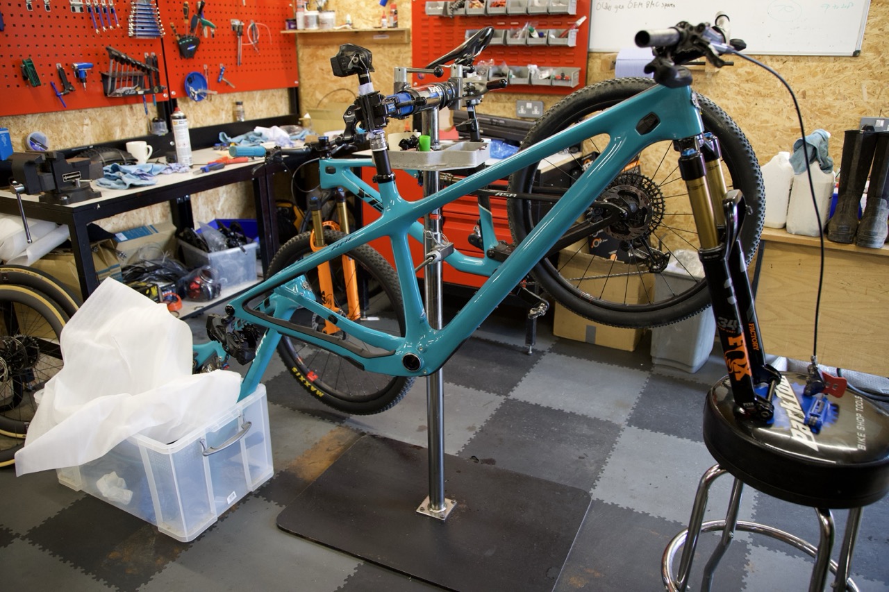 Turquoise Yeti ARC frame in a workshop stand with the serviced fork fitted